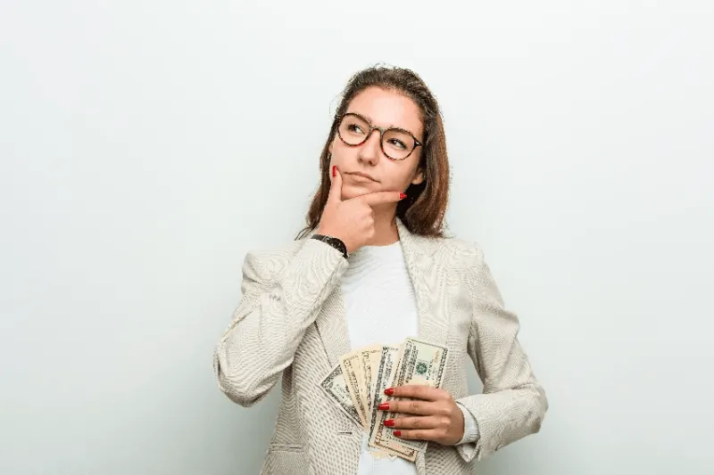 Young women thinking about Permanent Eyebrow Cost with holding money in hand