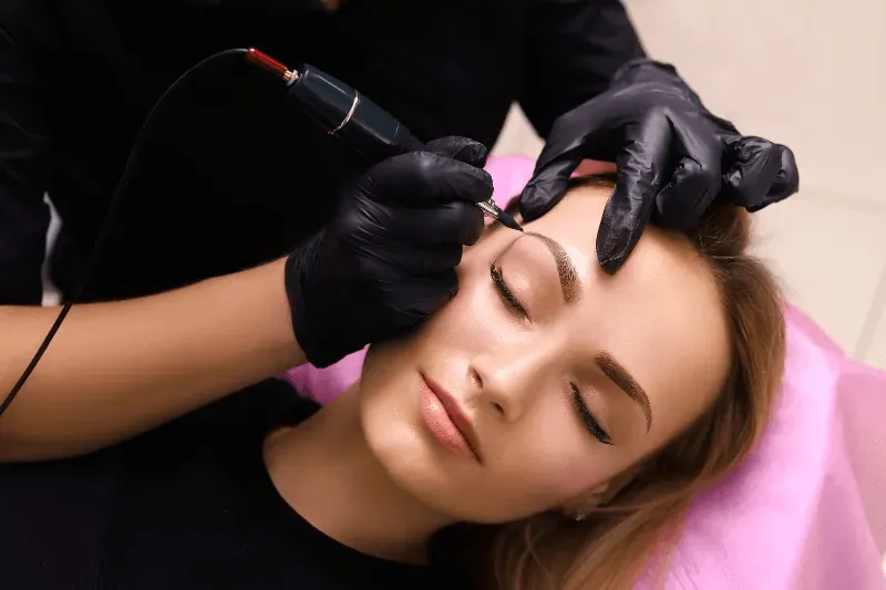 The image is focused on a person receiving a cosmetic procedure of permanent makeup.