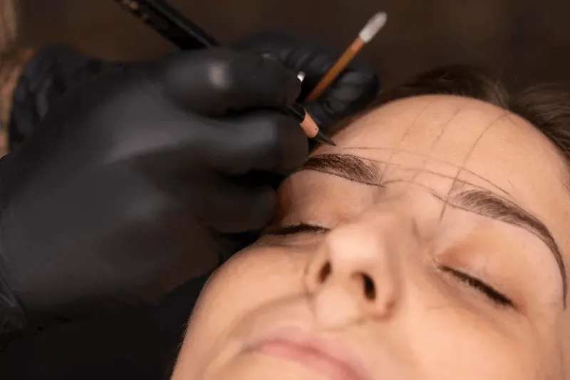 The image displays a close-up of a woman's face, highlighting the perfectly shaped and bold permanent eyebrows