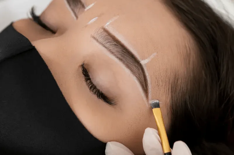 The image depicts the eyebrow lamination process, where precise markings are made before shaping and setting the brows.