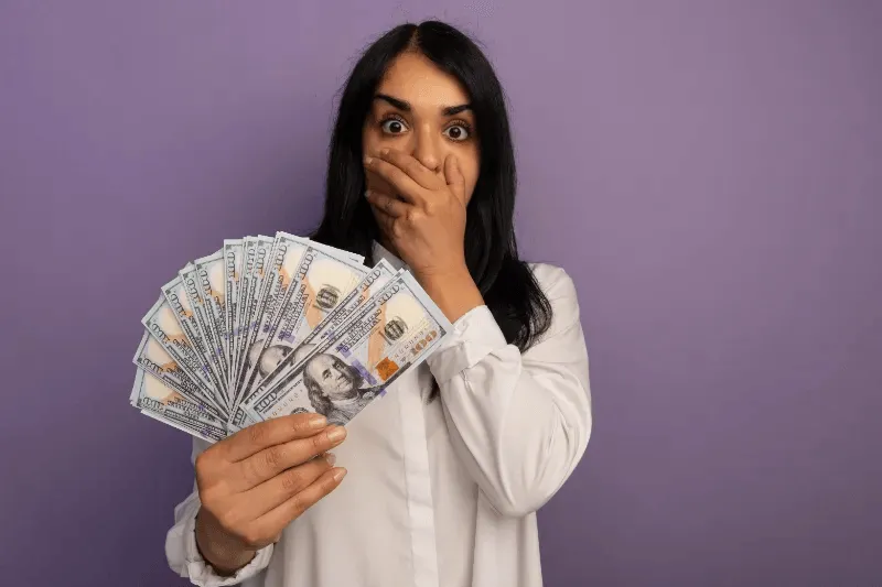 This image portrays a woman expressing surprise while holding a significant amount of money.