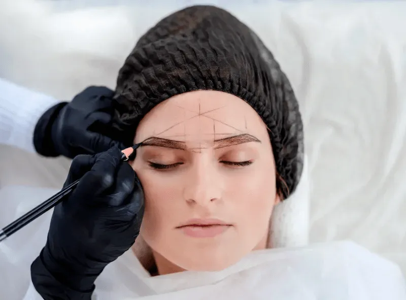 This image shows a woman undergoing the initial stage of permanent eyebrow shaping.