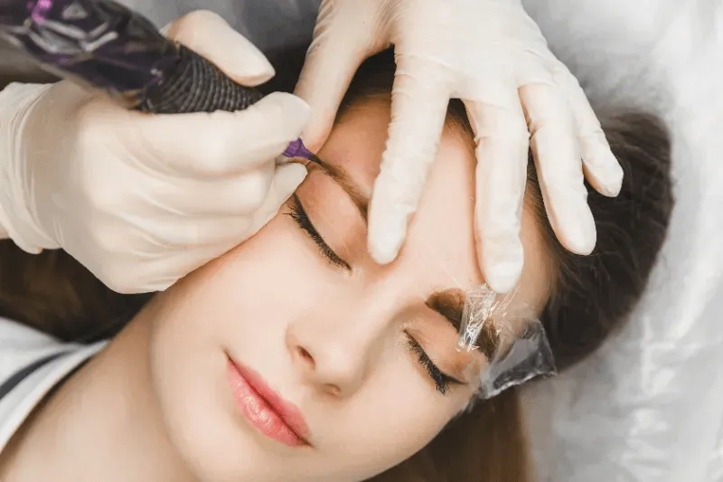 Professional applying brow lamination to enhance eyebrow shape and fullness.