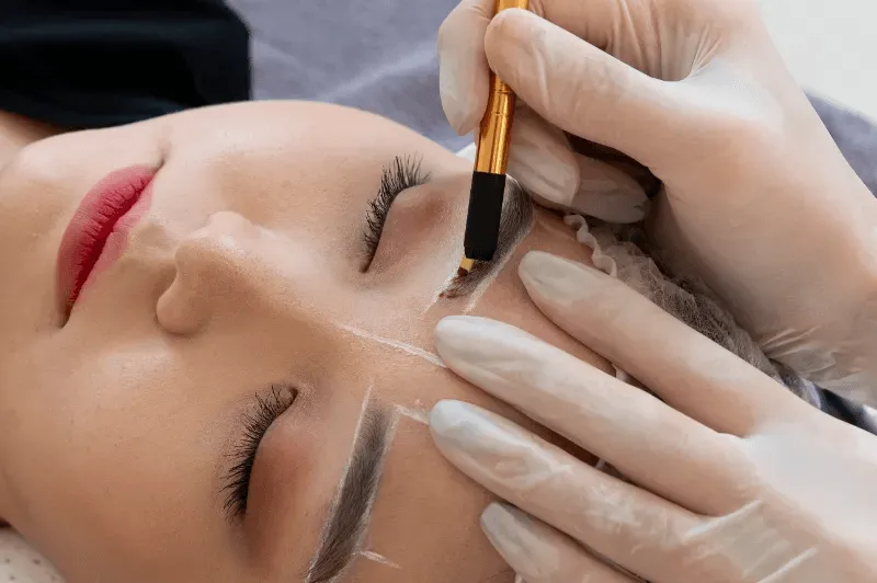 The image depicts a person receiving an eyebrow treatment